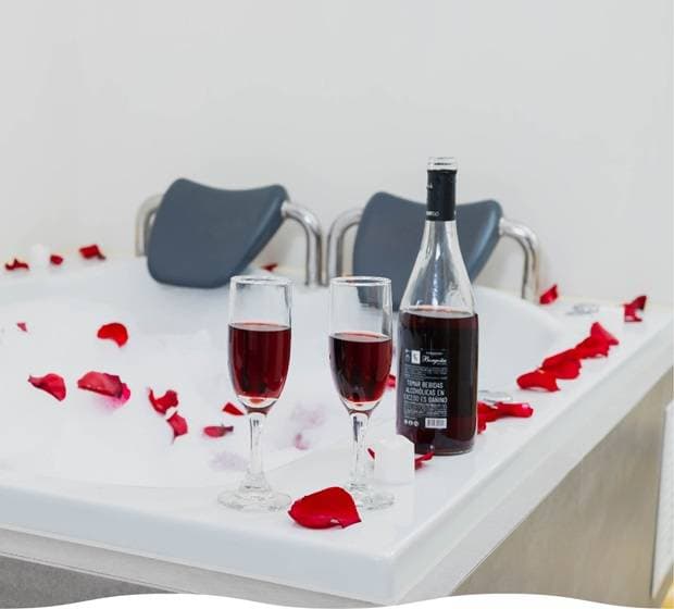 Jacuzzi de la suite con copas de vino y pétalos de rosa